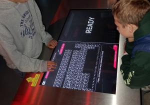 Uczniowie korzystają z interaktywnej tablicy Mendelejewa w centrum nauki.