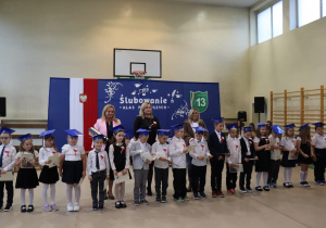 Grupa pierwszoklasistów prezentuje dyplomy podczas ślubowania w SP 13.