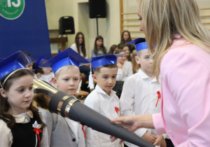 Dyrektor Anna Michalak pasuje pierwszoklasistkę na ucznia podczas uroczystości w SP 13.