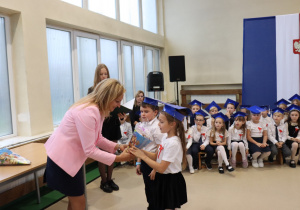 Dyrektor Anna Michalak odbiera symboliczny bukiet od uczennicy podczas ślubowania klas pierwszych w SP 13.