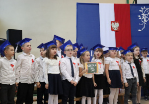 Pierwszoklasiści z planszą „Szkoła na tak” śpiewają podczas ślubowania w SP 13.