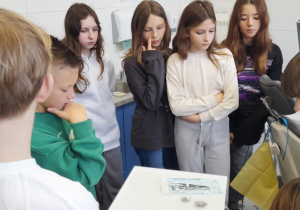 Uczniowie klasy 6a oglądają narzędzia dentystyczne przy fotelu w szkolnym gabinecie stomatologicznym.