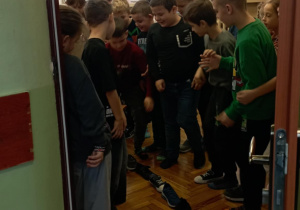 Uczniowie klasy 2b ustawiają buty jeden za drugim w drzwiach sali podczas andrzejkowej zabawy.