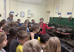 Przewodniczka objaśnia dzieciom działanie maszyn do produkcji bombek.