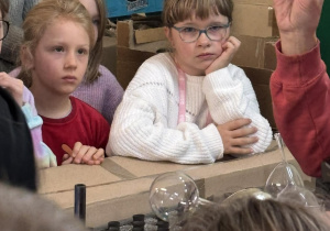 Uczennice przyglądają się z bliska szklanemu elementowi bombki prezentowanemu podczas zwiedzania.