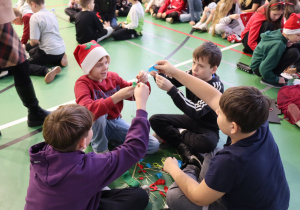 Uczniowie tworzą papierowy łańcuch podczas mikołajkowych zajęć kreatywnych.
