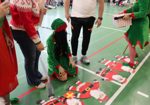Gotowe papierowe Mikołaje ułożone na podłodze podczas mikołajkowego wydarzenia.