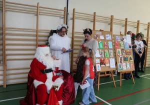 Uczennica przy Mikołaju; nauczycielka SP 13 prowadzi część oficjalną Mikołajek.