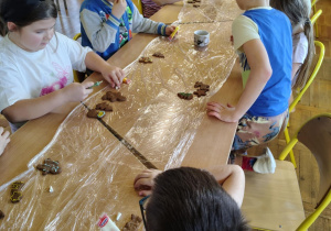 Dzieci w świetlicy szkolnej wspólnie dekorują pierniki przy jednym stole podczas zajęć świątecznych.