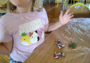 Uczennica świetlicy szkolnej pokazuje własnoręcznie udekorowane pierniki przygotowane podczas zajęć świątecznych.