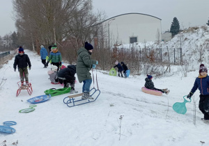 Uczniowie klasy 2b podczas zimowej zabawy na górce z sankami i jabłuszkami.