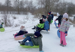 Uczniowie klasy 2b czekają na zjazd na górce z sankami i jabłuszkami.