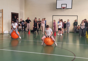 Uczniowie pokonują tor na piłkach do skakania w sali gimnastycznej.